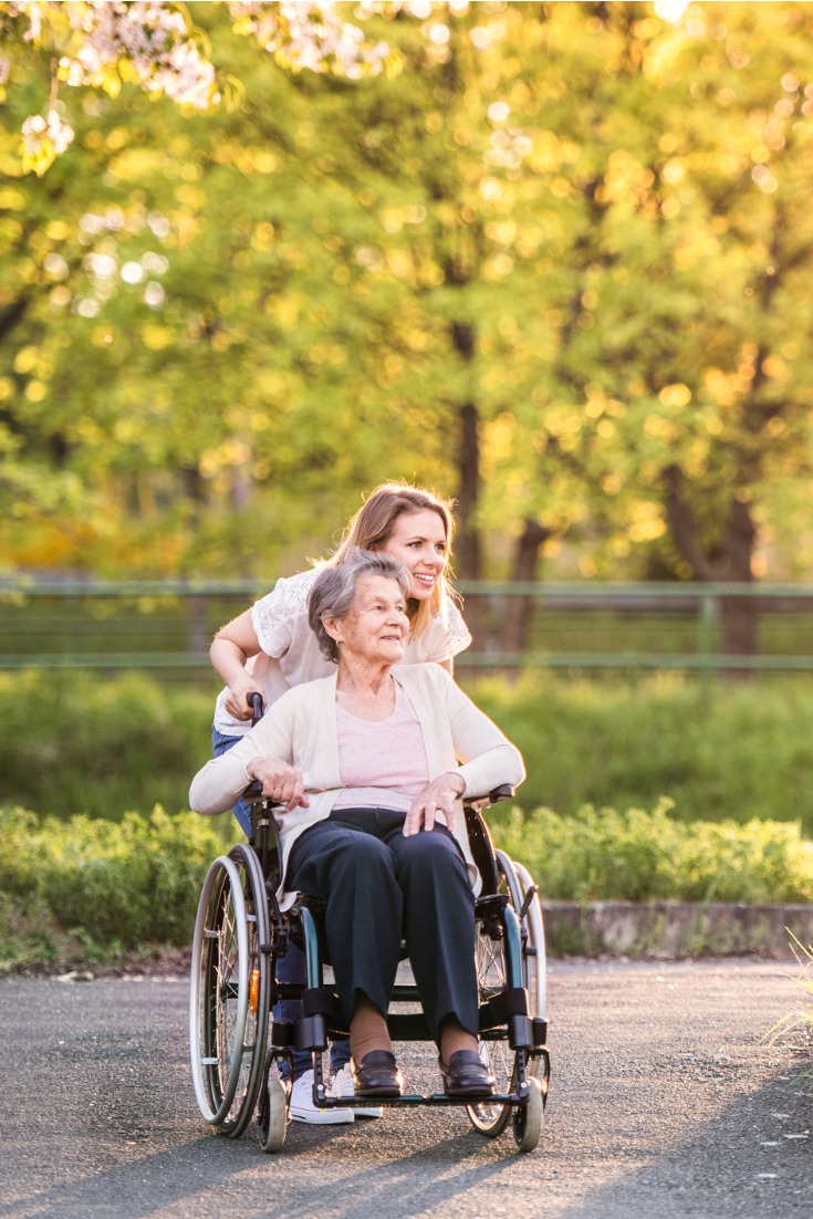 Elderly grandmother in wheelchair with granddaughter in spring nature