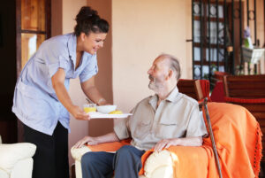 The Vital Role of Caregivers - carer bringing meal to senior man in residential home