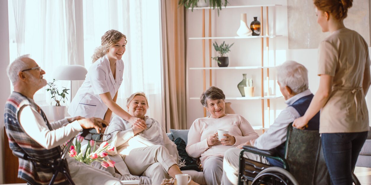 Disabled grandparents spending time in common room with their caregivers. November is National Family Caregiving Month